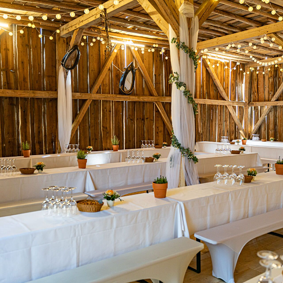 Überdachter Biergarten des Landgasthof Euringer Zwei lange Tafeln mit weißer Tischdecke stehen unter einem Holzdach, auch die Seiten sind mit Holz vor Wind und Wetter geschützt.