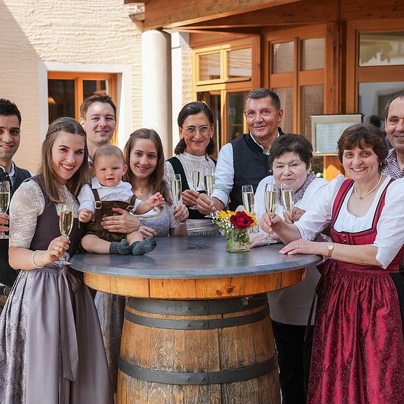 Das Team des Landgasthof Euringer Das gesamte Team des Landgasthofes Euringer ist in Tracht gekleidet und steht hinter einem Stehtisch mit einem Glas Bier in der Hand.