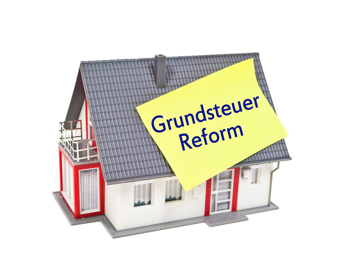 Haus mit Zettel und Grundsteuer Grundsteuerreform